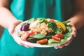 Salad vegetables with quinoa seeds on plate holding by hand Royalty Free Stock Photo