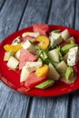 Salad with water-melon, arugula, feta cheese and avocado served on a red plate over rustic grey wooden table background. Royalty Free Stock Photo