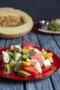 Salad with water-melon, arugula, feta cheese and avocado served on a red plate over rustic grey wooden table background. Royalty Free Stock Photo