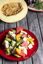 Salad with water-melon, arugula, feta cheese and avocado served on a red plate over rustic grey wooden table background. Royalty Free Stock Photo