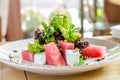 Salad with watermelon and herbs, on a white plate, on a wooden background, side view Royalty Free Stock Photo