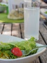 Salad in white bowl with glass of lemon water on wooden table Royalty Free Stock Photo