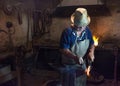 Salaj, Romania-May 12, 2018: Old blacksmith working hot metal horseshoe with hammer on the anvil in his vintage workshop in