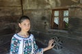 Salaj, Romania-May 12, 2018: Young girl wearing traditional Romanian costume sitting next to a old wooden church in Transylvania