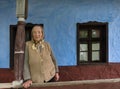 Salaj, Transylvania, Romania-May 15, 2018: old local woman in front of a rustic blue clay house in the rural countryside