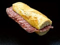 Salami sandwich, panino al salame, baguette and salami, isolated on black background Royalty Free Stock Photo