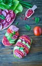 Salami sandwich with tomatoes and cucumbers next sliced salami and tomato and Basil leaves with salad on wooden background Royalty Free Stock Photo