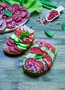 Salami sandwich with tomatoes and cucumbers next sliced salami and tomato and Basil leaves with salad on wooden background Royalty Free Stock Photo