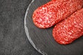 Salami sausage meat with bacon cut into circles close-up on slate stone plate round, dark background, top view, selective focus