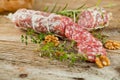 Salami sausages sliced with pepper, garlic and rosemary on cutting board on wooden table. Royalty Free Stock Photo