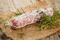 Salami sausages sliced with pepper, garlic and rosemary on cutting board on wooden table. Royalty Free Stock Photo