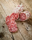 Salami sausages sliced with pepper, garlic and rosemary on cutting board on wooden table. Royalty Free Stock Photo