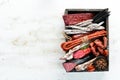 Salami, sausages, spices and meat products in a wooden box. Top view. Royalty Free Stock Photo