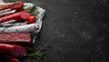 Salami and snacks. Sausage Fouet, sausages, salami, paperoni, on a black stone background. Top view. Royalty Free Stock Photo