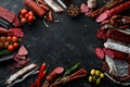 Salami and snacks. Sausage Fouet, sausages, salami, paperoni, on a black stone background. Top view.