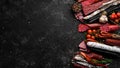 Salami and snacks. Sausage Fouet, sausages, salami, paperoni, on a black stone background. Top view. Royalty Free Stock Photo