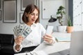 Salary raise notice. Overjoyed businesswoman holding money banknotes and looking at cellphone screen with excitement