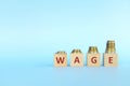 Salary or wage increase concept. Increasing stack of coins on wooden blocks in blue background.