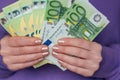 salary of a woman in the Eurozone.euro banknotes in female hands in a purple hoodie.Income of women