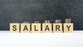 SALARY word, text written on wooden cubes on a black background with coins on cubes Royalty Free Stock Photo