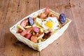 Salchipapa, roasted and sliced fresh Peruvian pork sausage, fried potato on wooden background.