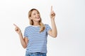 Sale and advertisement concept. Happy smiling blond girl makes choice, points sideways, shows left and right Royalty Free Stock Photo