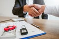 Sale agent handshake deal to agreement successful car loan contract with customer and sign agreement contract Insurance car