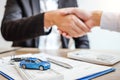 Sale agent handshake deal to agreement successful car loan contract with customer and sign agreement contract Insurance car