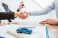 Sale agent handshake deal to agreement successful car loan contract with customer and sign agreement contract Insurance car