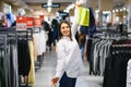 Sale, clothes , shopping, fashion and people concept - happy young woman choosing between two shirts in mall or clothing store Royalty Free Stock Photo