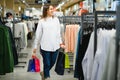 Sale, clothes , shopping, fashion and people concept - happy young woman choosing between two shirts in mall or clothing store Royalty Free Stock Photo