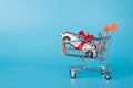 Sale concept. Close up photo of toy mini white car in miniature shopping cart isolated on blue background Royalty Free Stock Photo