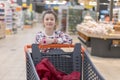 sale, consumerism and people concept - happy little girl with food in shopping cart at grocery store Royalty Free Stock Photo