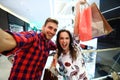 Sale, consumerism and people concept - happy young couple with shopping bags walking in mall. Royalty Free Stock Photo