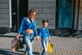 Sale, consumerism and people concept - happy young women her dauther with shopping bags walking city street Royalty Free Stock Photo