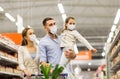 Family with shopping cart in masks at supermarket Royalty Free Stock Photo