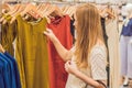 Sale, fashion, consumerism and people concept - happy young woman with shopping bags choosing clothes in mall or Royalty Free Stock Photo