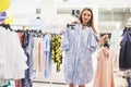 Sale, fashion, consumerism and people concept - happy young woman with shopping bags choosing clothes in mall or Royalty Free Stock Photo