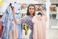 Sale, fashion, consumerism and people concept - happy young woman with shopping bags choosing clothes in mall or Royalty Free Stock Photo