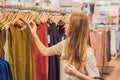 Sale, fashion, consumerism and people concept - happy young woman with shopping bags choosing clothes in mall or Royalty Free Stock Photo