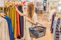 Sale, fashion, consumerism and people concept - happy young woman with shopping bags choosing clothes in mall or Royalty Free Stock Photo