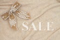 Sale message with gold bow with white snowflake on beige material