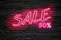 SALE 50 % Percent. fluorescent Neon tube Sign on dark brick wall. Front view. Can be used for online banner ads or background.