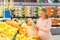 Pregnant woman with bag buying oranges at grocery Royalty Free Stock Photo