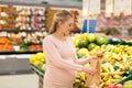 Pregnant woman with bag buying pears at grocery Royalty Free Stock Photo