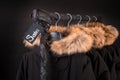 Sale sign. A lot of black coats, jacket with fur on hood hanging clothes rack. background. friday.Close up.