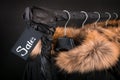 Sale sign. A lot of black coats, jacket with fur on hood hanging clothes rack. background. friday. Close up.