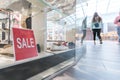 Sale sign in the shoe store shop window. Shoppers walk around the mall. Season sale, fashion and shopping concept Royalty Free Stock Photo