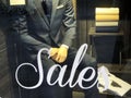 Sale sign on store window display. Male mannequin in suit close-up. Male clothes sales