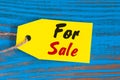 For Sale tag on blue wooden background. Sales, discount, advertising, marketing price tags clothes, furnishings, cars